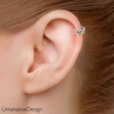 a woman's ear is shown with a small silver bow on the top of it