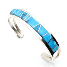 Indulge in the exceptional skill of Navaho artisan Sam Arviso with this meticulously made bracelet featuring Turquoise gemstones inlaid in a striking channel design. With a length of 5 1/4" and 1" opening, this bracelet is precisely crafted and not easily adjustable, ensuring its perfect fit. Its sleek 1/2" width and weight of approximately 27.4 grams make it a stunning and substantial piece for any jewelry collection. Elegant Turquoise Bracelet With Inlay, Elegant Turquoise Inlay Bracelet, Southwestern Style Blue Bangle Bracelets, Southwestern Style Blue Bangle Bracelet, Southwestern Style Jewelry Bracelet With Inlay, Blue Inlay Bracelet Jewelry, Southwestern Style Bracelet With Inlay, Blue Inlay Bracelet, Southwestern Inlay Bracelet