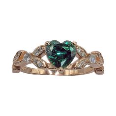 a green heart shaped ring with diamonds on it's sides and an arrow in the middle