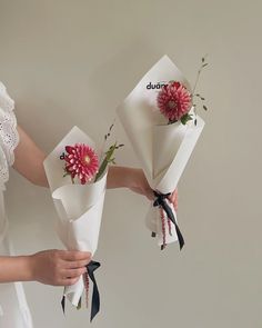 two women holding bouquets of flowers in their hands, one is pink and the other is red