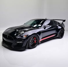 a black sports car with red stripes parked in a white studio area, it appears to be ready for the next race