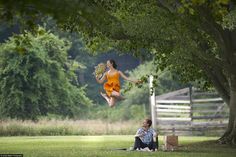 a woman in an orange dress jumping up into the air with a man sitting next to her