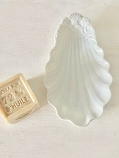 a soap bar sitting next to a small white shell shaped object on a table top