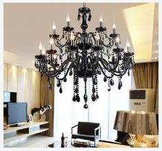 a black chandelier hanging from the ceiling in a living room next to a window