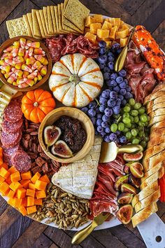 a platter filled with meats, cheeses, crackers and fruit on a wooden table