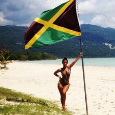 a woman in a bathing suit holding a flag on the beach