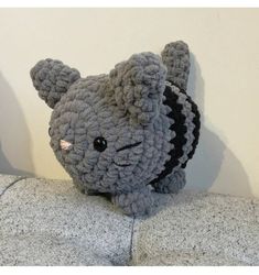 a gray stuffed animal sitting on top of a pillow