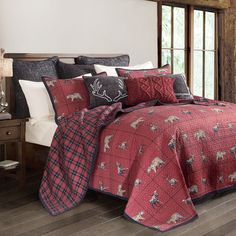 a bed covered in red and black plaid comforter with deer on the coverlet