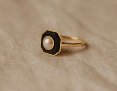 a close up of a ring with a pearl in the center on a cloth background