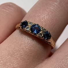 a woman's hand with a yellow gold ring with blue and white stones on it