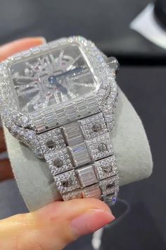 a person holding up a watch with diamonds on it's face and bracelet around the wrist