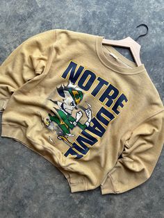 Vintage 90's Notre Dame Fighting Irish University Custom Dyed Crewneck Sweatshirt  Size approx Medium Large 22x25  Super Soft Fleece  Custom Dyed to a light gold color  double sided great graphic  Any questions feel free to reach out! Vintage Acid Wash Crew Neck Sweatshirt, Vintage Gold Top With Graphic Print, Vintage Gold Tops With Graphic Print, Gold Vintage Tops With Graphic Print, Vintage Gold Crew Neck Top, Vintage Yellow Crew Neck Sweatshirt, Gold Crew Neck Sweatshirt For Fall, Notre Dame Game Day, Light Gold Color