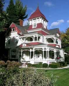 a large white and red house sitting on top of a lush green field