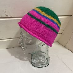 Most of this hat is bright, almost neon pink, with stripes of green and mustard. The end result has a distinctive visual energy to it, as the colors interact with one another in an unusual way. The bottom of the hat has a rolled brim, and the top is smooth and rounded. This hat is structured and handmade. It was knit and felted by hand using 100% secondhand wool yarn in a smoke-free environment. This hat is sized for an adult and suitable for all genders. Enjoy! The hat will arrive in 100% compo Fun Pink Beanie Hat, Retro Pink Brimmed Hat, Fun Pink Hat, One Size, Green Brimmed Beanie, One Size Fits Most, Green Brimmed Beanie (one Size Fits Most), Retro Multicolor Short Brim Hat, Funky Pink Cap Hat, Multicolor Brimmed Beanie, One Size Fits Most, Multicolor Brimmed Beanie (one Size Fits Most)