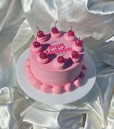 a birthday cake with pink frosting and cherries on top