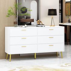 a large white dresser with gold handles in a living room next to a black lamp