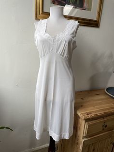 This is such a classic, pretty little slip dress or nightgown, in 100% white nylon with delicate lace details at the straps, bust, and hem. In excellent vintage condition. Marked as a UK size 16 (see photos for measurements) but I'd say it's closer to a modern UK 10-12. All items listed in Attic 1 Shop are vintage and pre-owned/pre-worn unless explicitly stated in the listing. Please be aware that this means items are not in brand new condition and you must read item descriptions thoroughly to e Summer Nightgown With Spaghetti Straps And Lace Trim, Summer Sleeveless Nightgown With Delicate Lace, Summer Sleeveless Delicate Lace Nightgown, Sleeveless Delicate Lace Summer Nightgown, Summer Camisole Nightgown With Lace Trim, White Midi Length Slip Dress With Lace Trim, White Midi Slip Dress With Lace Trim, White Lace Trim Slip Dress For Sleep, White Slip Dress With Lace Trim And Spaghetti Straps