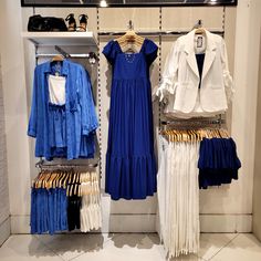 clothes on display in a clothing store with white and blue outfits hanging from the racks