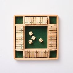 two dices and four dominoes in a wooden box on a white surface with green felt