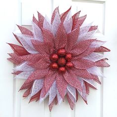 a red and white christmas wreath hanging on a door