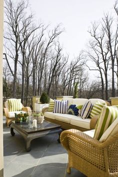 an outdoor living room with wicker furniture and green striped pillows on the couches