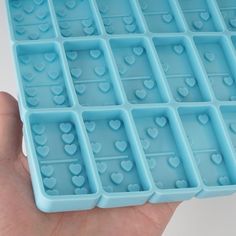 a hand holding an ice tray with hearts on it