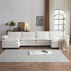 a living room with white furniture and wood flooring, including a large sectional couch