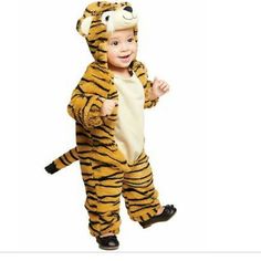 a little boy in a tiger costume is standing on one leg and smiling at the camera