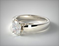 a white gold engagement ring with a round brilliant cut diamond in the center, on a plain surface