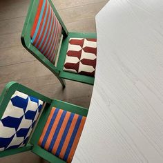 two colorful chairs sitting next to each other on top of a wooden floor