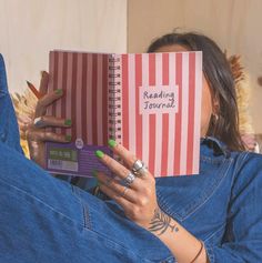 a woman is reading a book while laying on her stomach and holding it up to her face