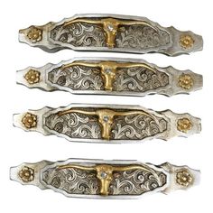 three silver and gold metal handles with decorative designs on them, one has a cross in the center