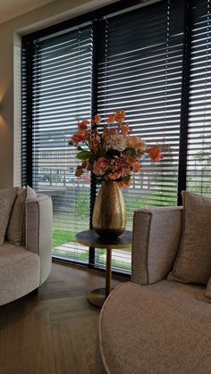 a living room with two couches and a vase filled with flowers