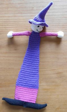 a crocheted doll wearing a purple and pink dress on top of a wooden table