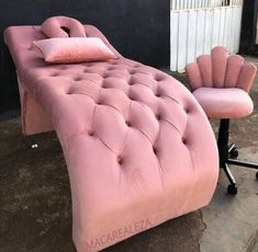 a pink chaise lounge chair and footstool in front of a black wall