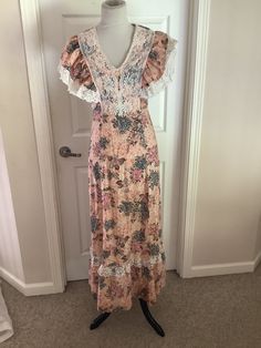 This nice vintage 70s peach burgundy green floral lace bib high waisted Maxi hippie dress comes to you in a size S. As you can see from pictures lace bodice over and then ties in back. Looks to be handmade cannot find a tag. Up material etc points to 70s dress.pls compare the measurements I give you to those in your closet. Overall great cond. 17 1/4 underarm to underarm -14/inches waist across- hips n/a-46 1/4 inches underarm to bottom of dress. Vintage V-neck Dress For Garden Party, Bohemian Flowy Dress With Lace Bodice, Flowy Bohemian Dress With Lace Bodice, Bohemian Dress With Lace Bodice For Garden Party, Bohemian Lace Bodice Dress For Garden Party, Bohemian Floral Print Dress With Empire Waist, Bohemian Fitted Maxi Dress With Lace Patchwork, Fitted Bohemian Maxi Dress With Lace Patchwork, Summer Floral Print Lace Maxi Dress