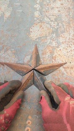 a person wearing pink gloves standing in front of a rusty star on the cement floor