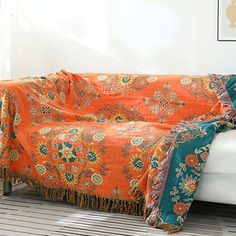 an orange and blue blanket sitting on top of a white couch