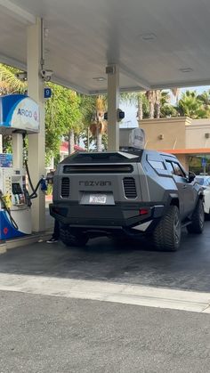 an suv is parked in front of a gas station with two other vehicles at the pump