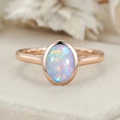 a white opalite ring sitting on top of a cloth covered surface with flowers in the background