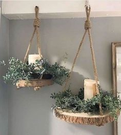 two hanging planters with candles and greenery on the top are hung from rope