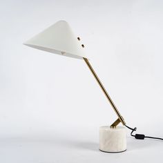 a white table lamp with a black cord attached to the base on a white background