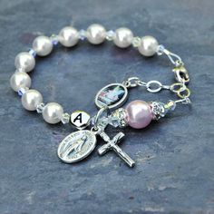 Celebrate the Baptism of a baby girl with this beautiful white and rosaline pink guardian angel rosary bracelet. The bracelet features genuine Swarovski crystals and crystal pearls throughout. The bracelet has white Swarovski pearls for the Hail Mary prayers and just a touch of rosaline pink with the larger Our Father pearl. In between are sparkly Swarovski crystals with an aurora borealis finish. The Our Father pearl is surrounded by crystal rhinestone rondelles. If you select the personalizati Spiritual Pink Jewelry For Birthday, White Bracelet For First Communion, White Bracelet Jewelry For First Communion, White Adjustable Bracelet For Confirmation, Adjustable White Bracelet For Confirmation, Personalized Spiritual Bracelets For First Communion, White Hypoallergenic Pearl Bracelet For First Communion, Hypoallergenic White Pearl Bracelet For First Communion, Adjustable Rosary Bracelet With Miraculous Medal For First Communion