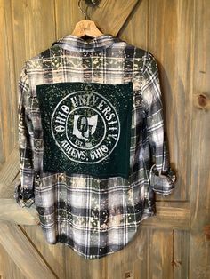 Artfully distressed, upcycled and sustainable flannel shirt paired with upcycled tee with graphic.  Unisex in style but sourced from a variety of brands so resized for a roomy women's fit.  All one of kind and unless noted, flannel is medium weight.  Show your pride with a unique spirit wear  that only you will have. Embellished Flannel Shirts, Casual Flannel Shirt With Graphic Print, Casual Flannel Patchwork Top, Casual Flannel Top With Patchwork, Casual Fall Tops With Patches, Plaid Flannel Tops With Graphic Print, Fall Graphic Print Flannel Shirt, Fall Flannel Shirt With Graphic Print, Fall Flannel Top With Graphic Print