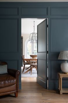 an open door leading into a living room with blue walls and leather furniture in the foreground