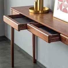 a wooden desk with two drawers and a cell phone on the table next to it