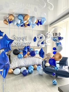 blue and white balloons are hanging from the ceiling in this room with a bed, chair, and couch