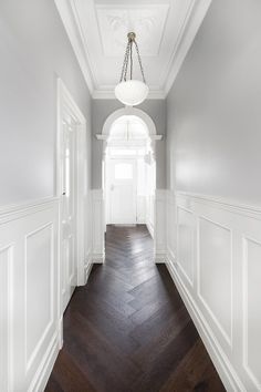 an empty hallway with white walls and wood floors