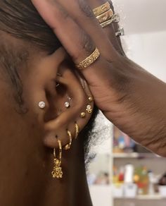 a close up of a person's ear wearing gold jewelry