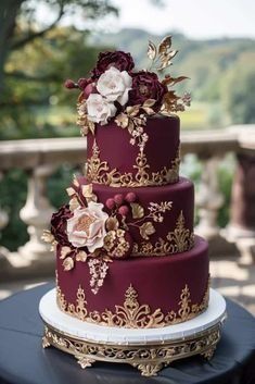 a three tiered wedding cake with flowers on the top and gold trimmings